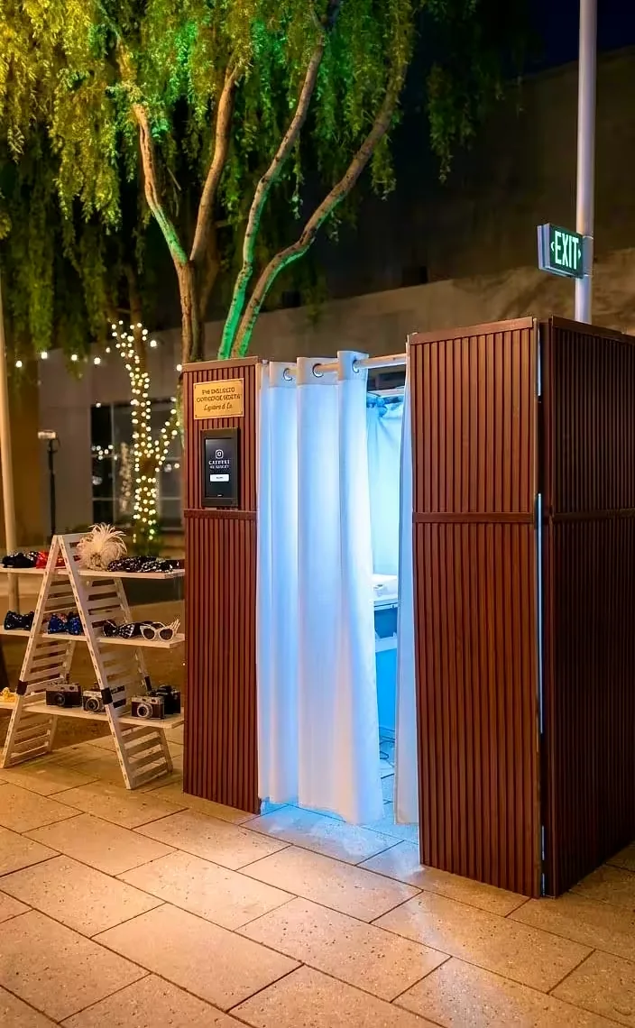 Enclosed wooden photo booth with an illuminated Photo Booth sign