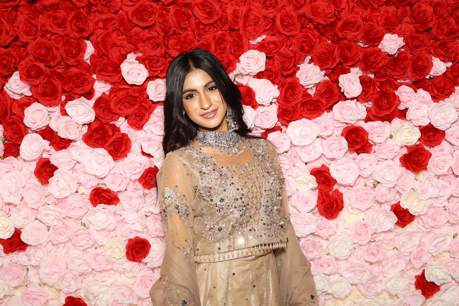 Guest posing against a red and pink rose backdrop