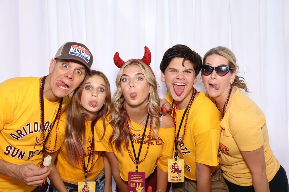 Event guests in Arizona State colors posing with photo booth props