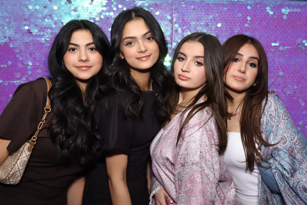 Four guests posing in front of an iridescent sequin backdrop